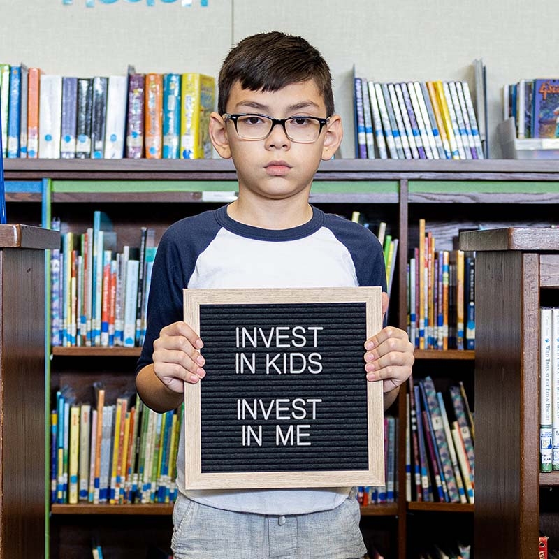 A boy holds a black and white sign that reads, SCAN.