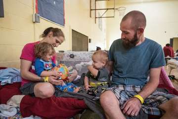 Shelby and Nick play with their children, 2-year-old Sarah*, and 1 -year-old Aaron*, on their cot in a shelter in San Antonio, Texas, on August 27, 2017.