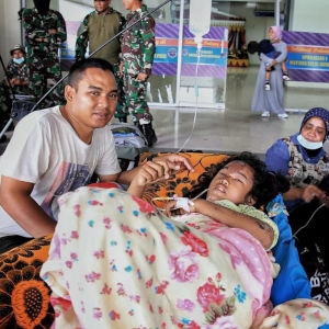 Puri*, 9, with her brother, Dimas*, 33, await an emergency plane in Palu, Indonesia to take them to Makassar for treatment. Puri was buried under rubble and suffered a serious head injury in the earthquake that struck Indonesia on September 28, 2018. *name has been changed. Photo Credit: Junaedi Uko / Save the Children.