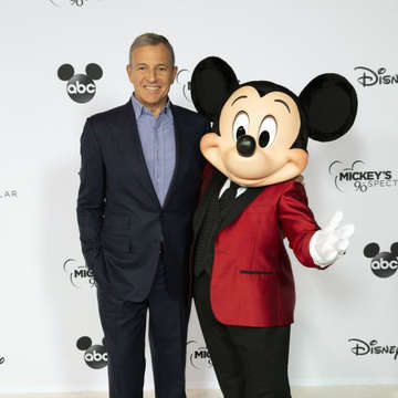 Robert Iger and Mickey Mouse together smiling.