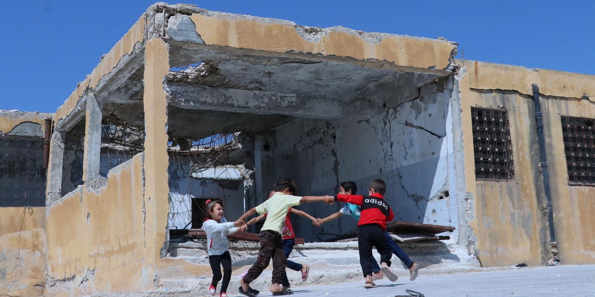 Children that may not be going to school this year, play outside their school in Idlib Syria.