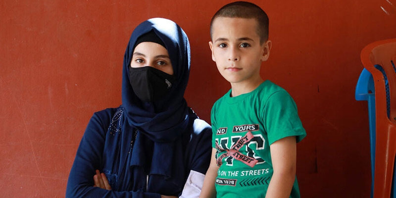 In Lebanon, two siblings sit together, with the older sibling crossing her arms.