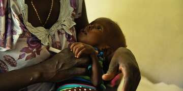 A one year old girl in her mothers arms in South Sudan