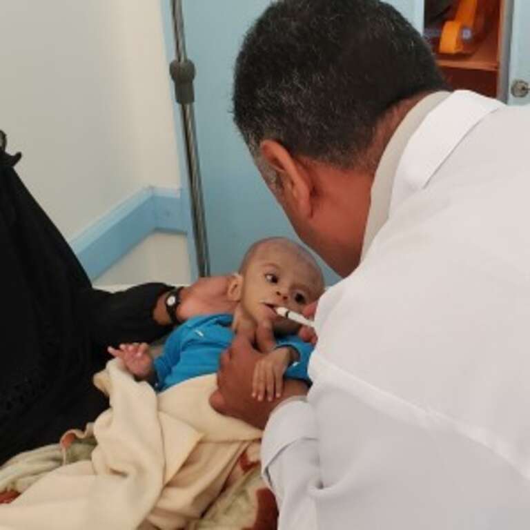 One-year-old Haifa* is held by her mother Roqea* as she is treated for malnutrition at a treatment center in Taiz, Yemen in January 2021.