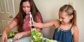 Children prepare a garden salad together with ingredients provided by a Save the Children meal kit.