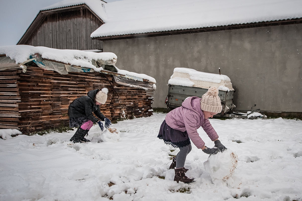 Two young Ukrainian refugee children play in the snow in Romania