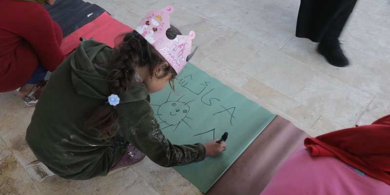A child draws while participating in activities at child-friendly space in Syria