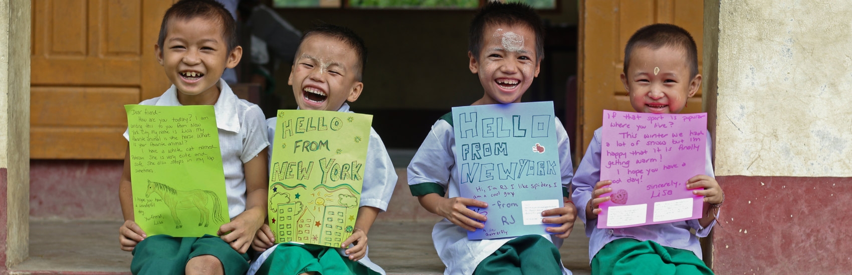Four young boys in Myanmar hold up their Save the Children sponsor letters. Photo Credit: Save the Children Vietnam 2020.