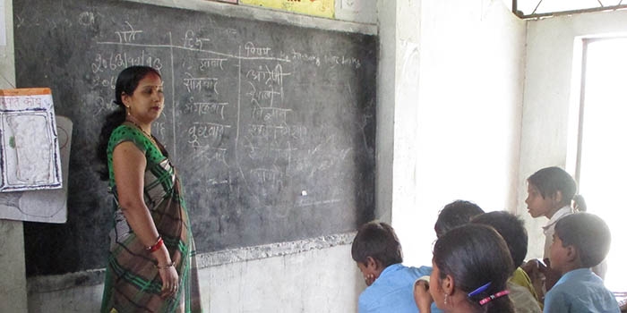 Teacher Mira stands in front of a class teaching in Nepal.