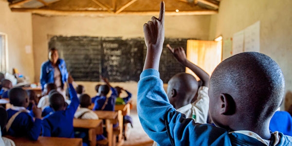 In Tanzania, students in a classroom raise their hands during a lesson.