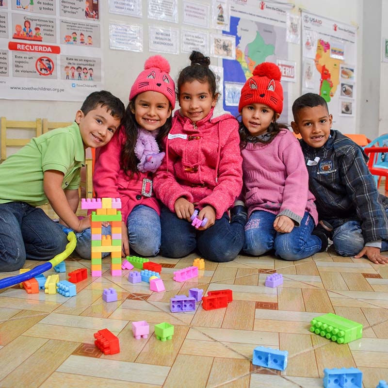 Five children pose for the camera with funny expressions with building blocks in the child-friendly space that Save the Children installs during the delivery of economic assistance to vulnerable Venezuelan families in Lima.