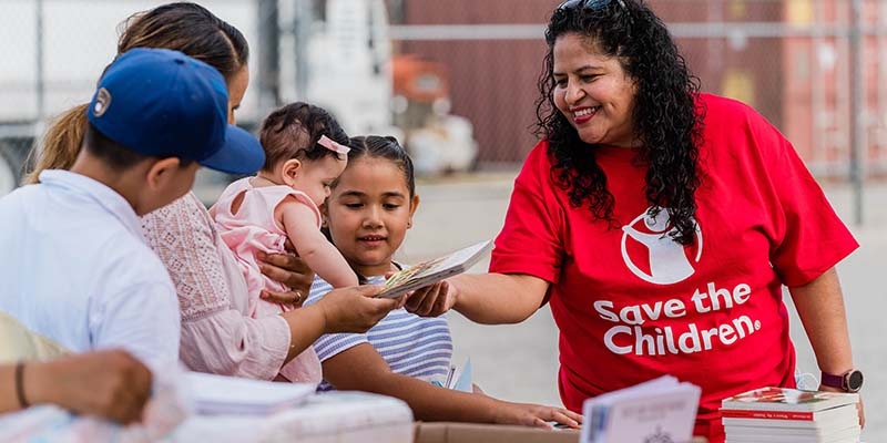 A save the children staffer hands out food to families. 