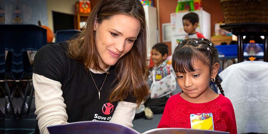 Дженнифер Гарнер, актриса и попечитель организации «Спасем детей», читает с ребенком.
