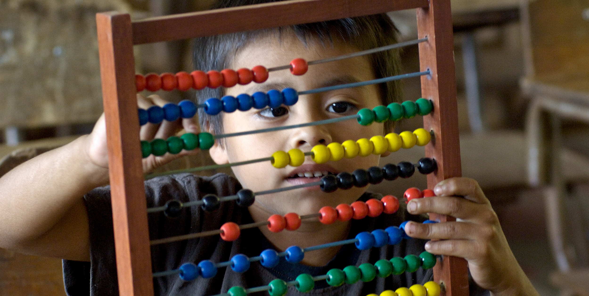 A young boy plays with an abacus.