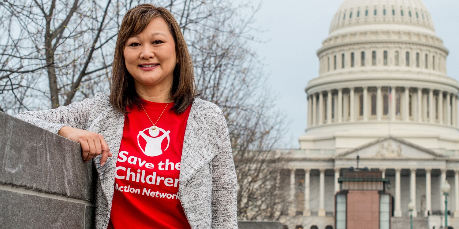 A woman wearing a red Save the Children Action Network t-shirt and stands in front of the Capitol Building in Washington D.C. Photo credit: Susan Warner/Save the Children, March 2017.