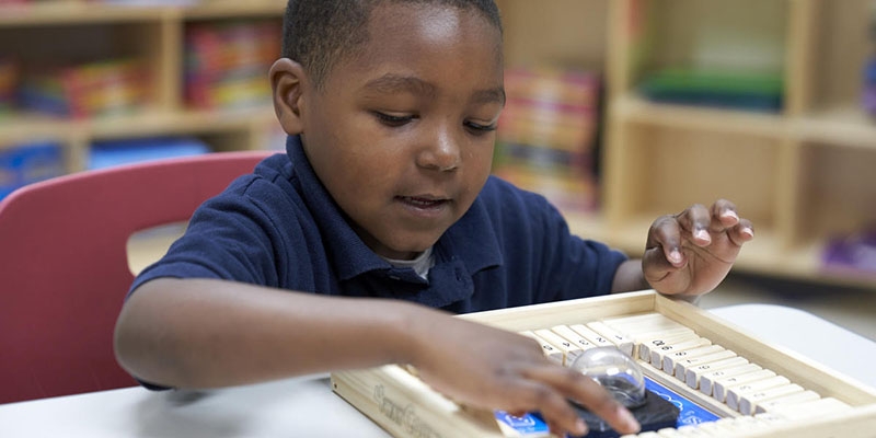 A young boy uses a math tool at a desk.