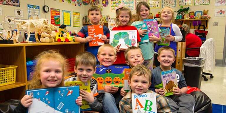 A group of first grade students hold up favorite books in their classroom in Kentucky.