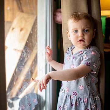 A 2-year old girl stands in front of a window at her home in rural West Virgina. 