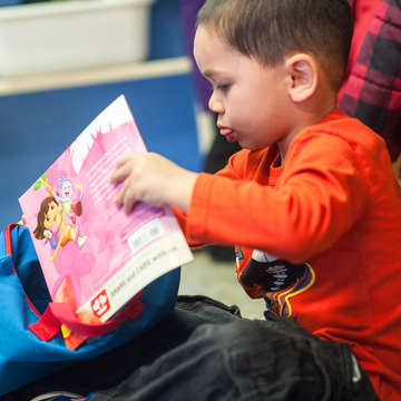 Preschooler Ryder, 3 with his "Raising a Reader" book bag. The book exchange program lets provides a different set of books weekly for students to take home. Save the Children supports the Queets Head Start program through it's Early Step of School Success porgram. Photo credit: Susan Warner / Save the Children 2015.