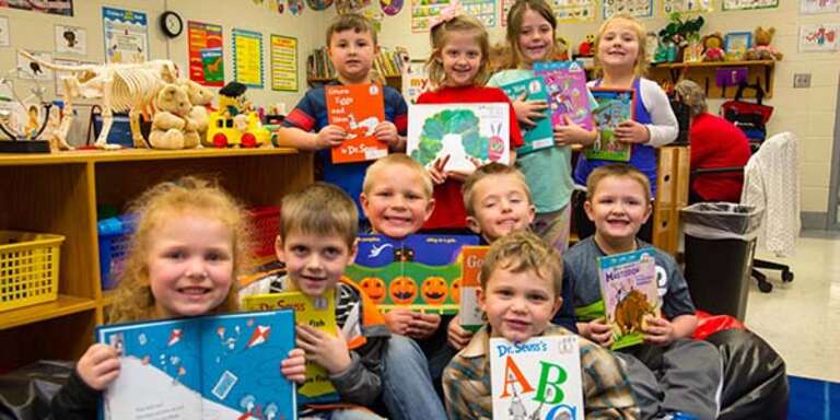 A group of first grade students hold up favorite books in their classroom in Kentucky. They are part of Save the Children's in school emergent reader program which provides training, tools and support schools need to accelerate reading growth for struggling readers. March 2018