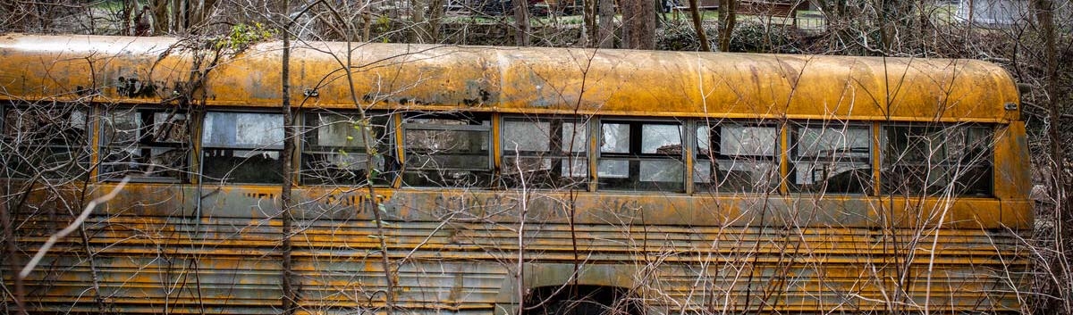An abandoned school bus sits in a wooded area in rural America where rates of child poverty are high