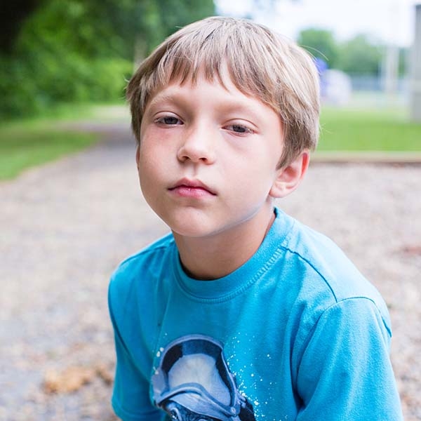 A young boy wears a blue t-shirt while sitting outside in Tennessee.