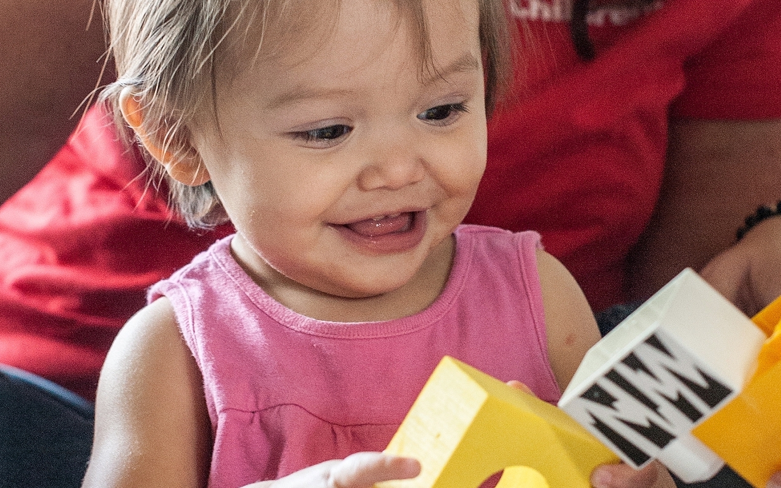 A young girl plays with yellow blocks.