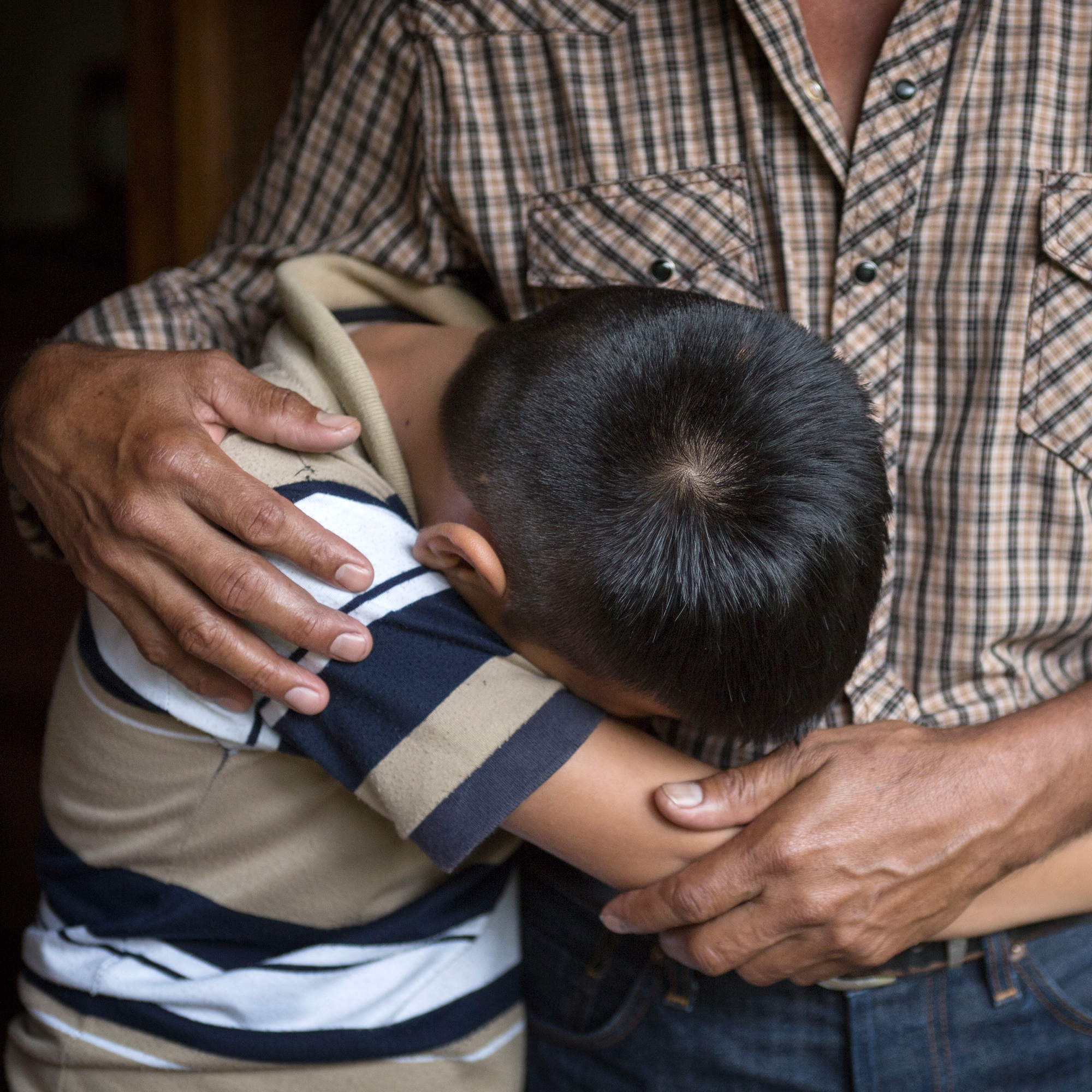 An El Salvadorian father comforts his 12-year old son. The boy lost his older brother to gang violence and the family cannot return home as a result. Save the Children is gravely concerned about the treatment and well-being of children from Central America and Mexico who are in the custody of the United States government after crossing the U.S.-Mexico border. Photo credit: Tom Pilston / Save the Children, May 2017