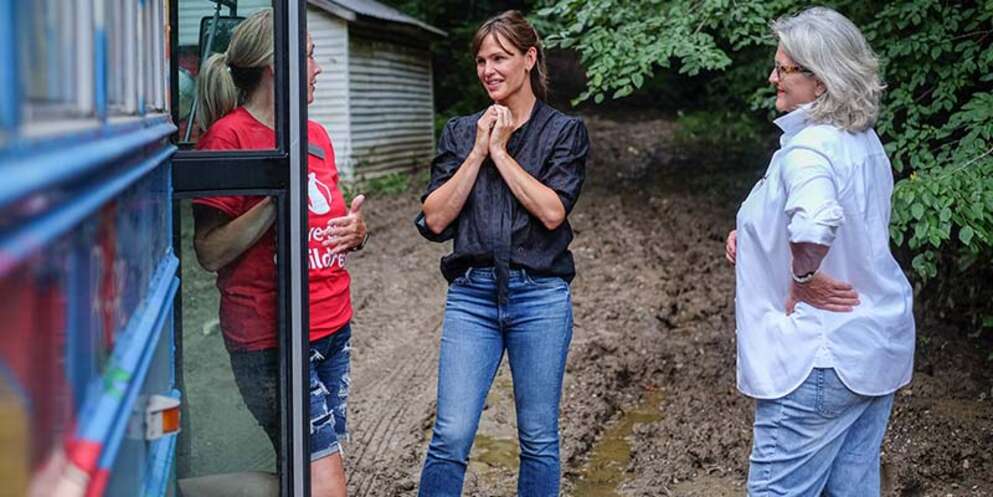 Save the Children staff member Kim Bolling, left, with Actor and Save the Children Trustee Jennifer Garner, center, and NBC News Correspondent Cynthia McFadden stand beside Rosie the Readiness Bus as they deliver aid to families impacted by the flooding in Kentucky.