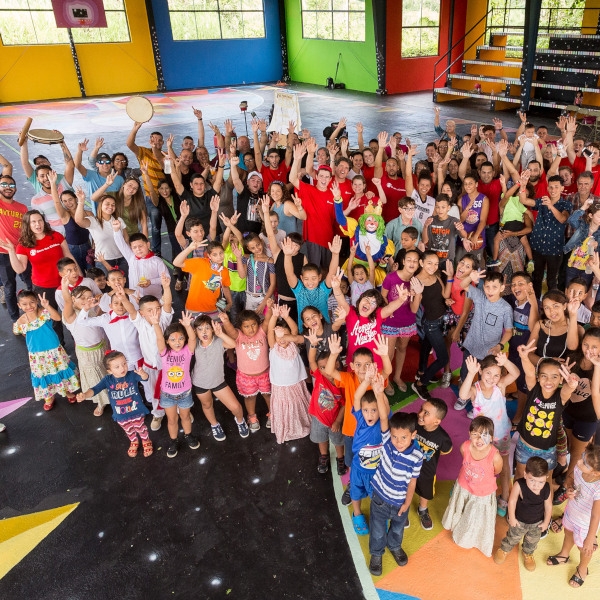A group photo of residents of Ciales, Puerto Rico as they celebrate their completion of a mural (by artist Okuda San Miguel) at a community basketball court. The project is part of Save the Children’s long-term child resilience plan, as Ciales rebounds after Hurricane Maria in September 2017. Photo credit: Gabriel Gonzalez / Save the Children, December 2017.  