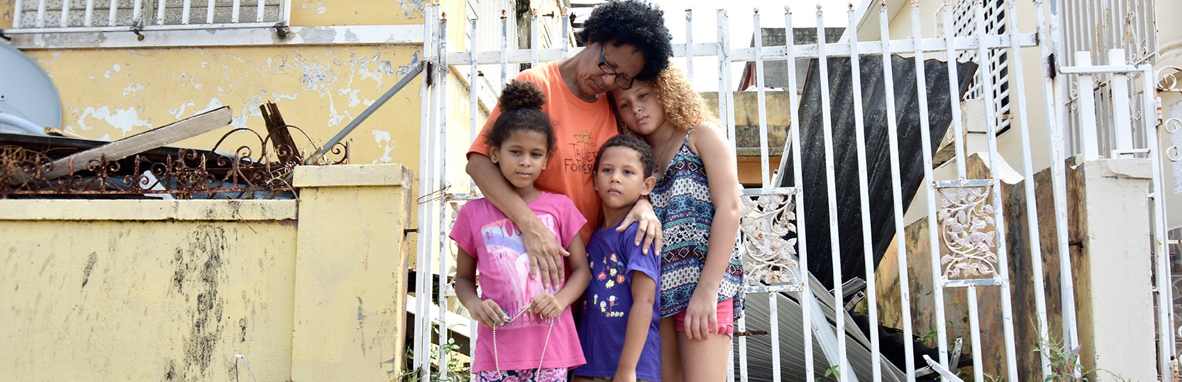 A grandmother embraces three of her grandchildren amid debris and rubble caused by Hurricane Maria.