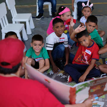 A group of children enjoys story time lead by Save the Children Education Coordinator Maritza Erazo during a community event at the Mulitas Community Center in Puerto Rico. Photo credit: Shawn Millsaps / Save the Children 2018.