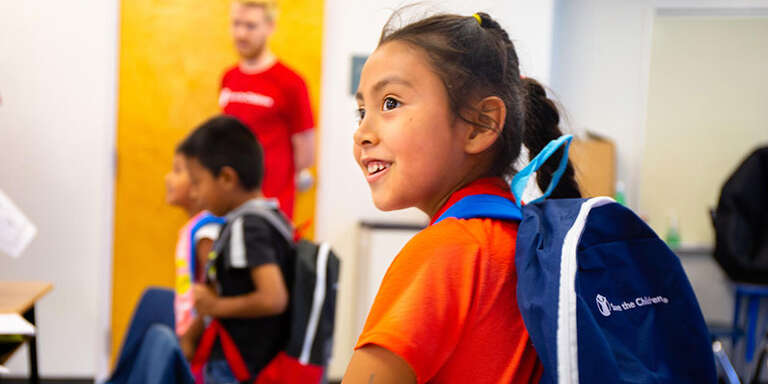 A smiling girl wearing a backpack.