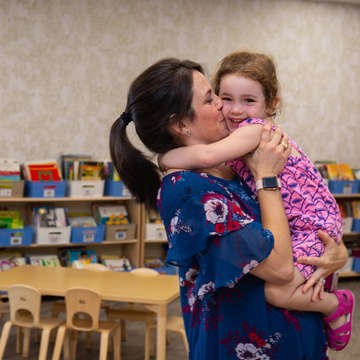 Marisa hugs her daughter Caley, 3, at her daycare in Texas. They’re standing in a newly refurbished library that was destroyed in Hurricane Harvey, 2017. Save the Children funding helped rebuild the new library, as well as the daycare’s infant and toddler playground, and occupational therapy gym. Save the Children, June 2018.