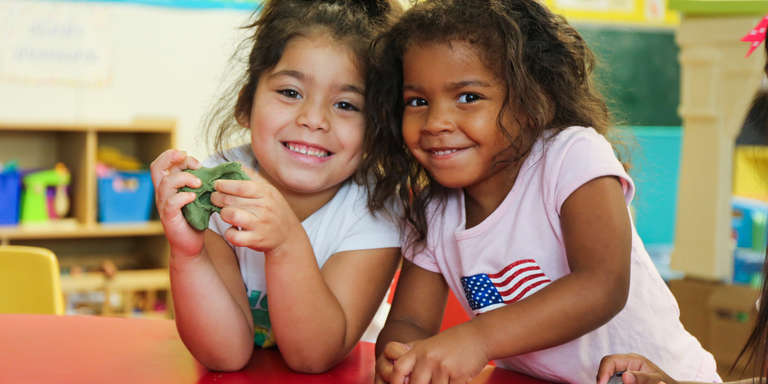 Two young girls smile while playing at a table inside a designated safe area designed by Save the Children in the aftermath of Hurricane Harvey.