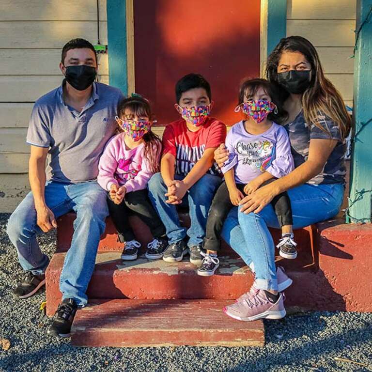 A family of five sit outside of thier home in Central Valley, CA while wearing cloth face masks to protect against the spread of COVID-19.