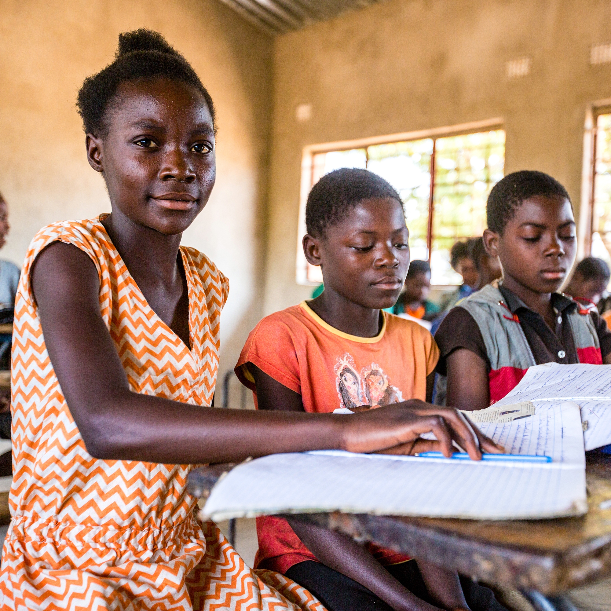 A 12-year old girl in Zambia sits in a classroom among other students. She participates in a basic education program made possible through sponsorship. Photo Credit: Victoria Zegler/Save the Children, October 2016. 